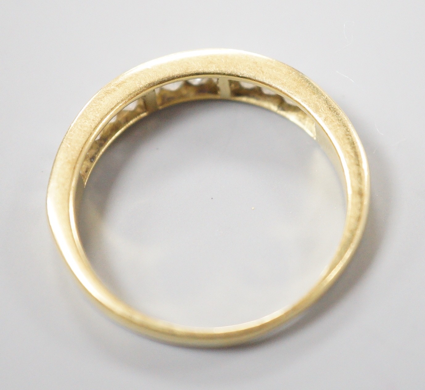 A modern 18ct gold and graduated baguette cut diamond set half eternity ring, size Q, gross 3.4 grams.